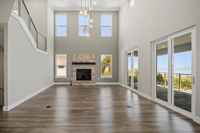 unfurnished living room featuring crown molding, a water view, plenty of natural light, and a fireplace