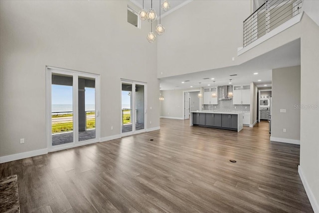 unfurnished living room with a notable chandelier, dark wood-type flooring, and a high ceiling