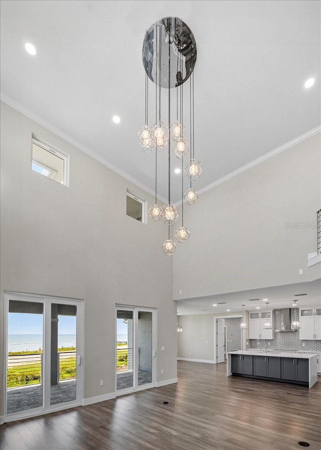 unfurnished living room with a towering ceiling, ornamental molding, and dark hardwood / wood-style floors