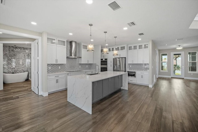 kitchen featuring appliances with stainless steel finishes, wall chimney range hood, and white cabinets