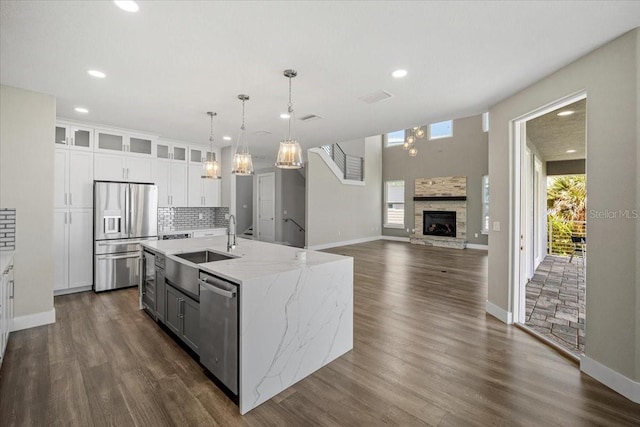 kitchen with white cabinetry, appliances with stainless steel finishes, an island with sink, and backsplash