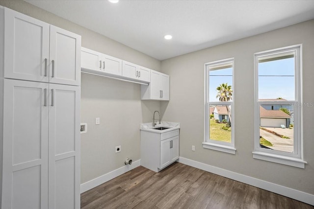 laundry area with cabinets, wood-type flooring, hookup for an electric dryer, and sink