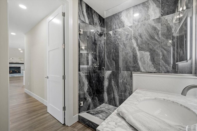 bathroom featuring sink, hardwood / wood-style floors, a fireplace, and walk in shower