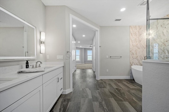 bathroom featuring ceiling fan, vanity, and plus walk in shower