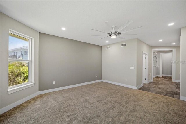 spare room featuring ceiling fan and dark colored carpet