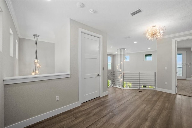 empty room with crown molding, hardwood / wood-style floors, and a notable chandelier