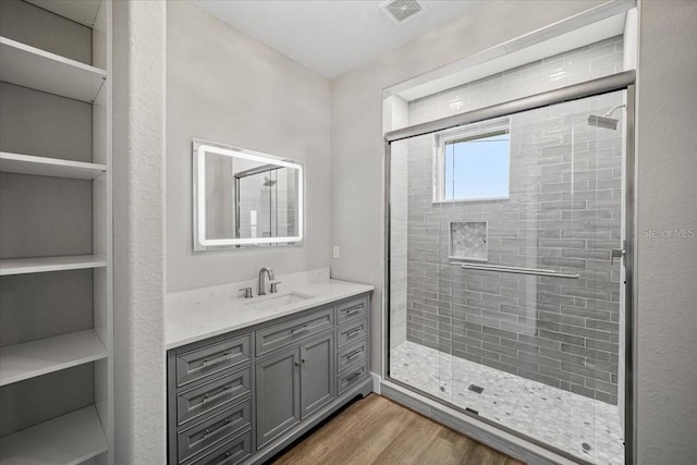 bathroom with wood-type flooring, vanity, and walk in shower