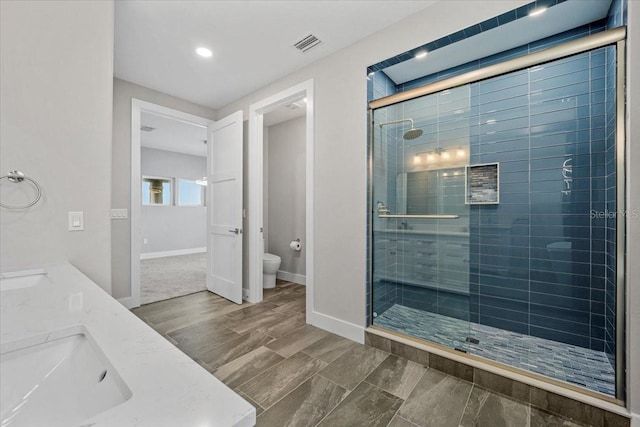 bathroom featuring vanity, toilet, and a shower with shower door