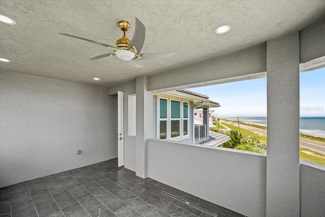 balcony featuring a water view, ceiling fan, and a view of the beach