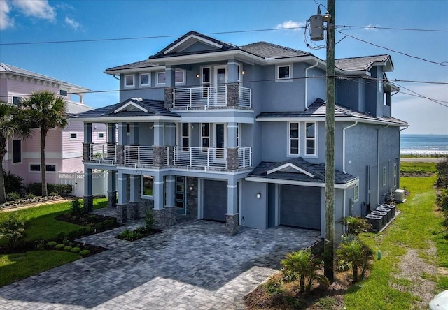 view of front of property with a garage, a balcony, a water view, and central air condition unit