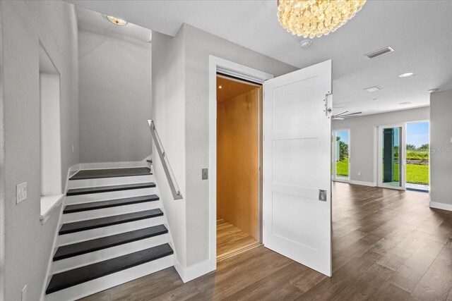 stairway featuring wood-type flooring and an inviting chandelier