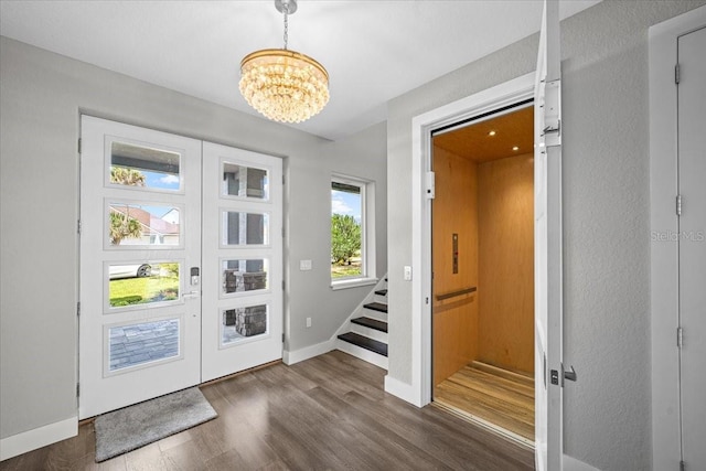 foyer featuring french doors, dark hardwood / wood-style floors, and a notable chandelier