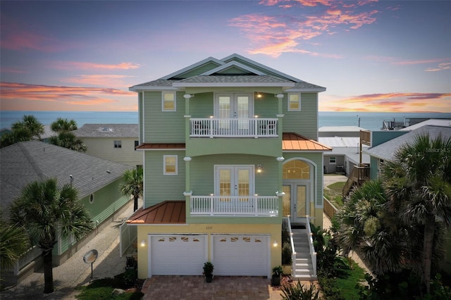 view of front facade with french doors, a water view, and a garage