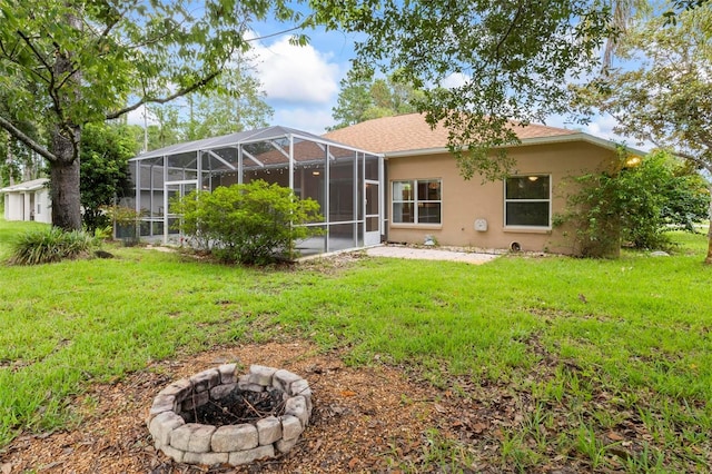 rear view of property featuring a lanai, a lawn, and a fire pit