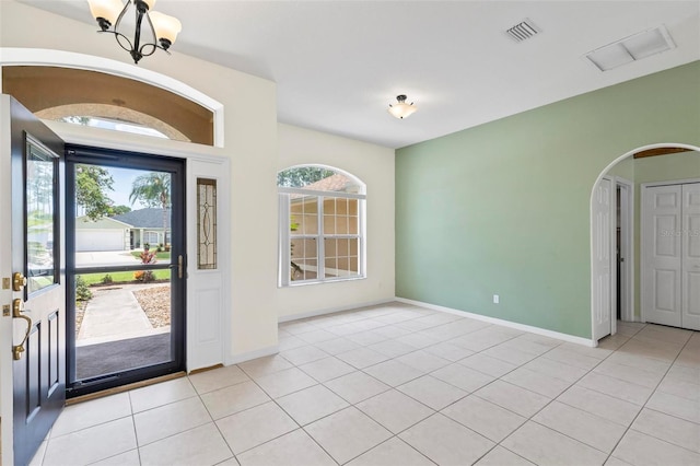 tiled foyer entrance featuring a notable chandelier and a healthy amount of sunlight