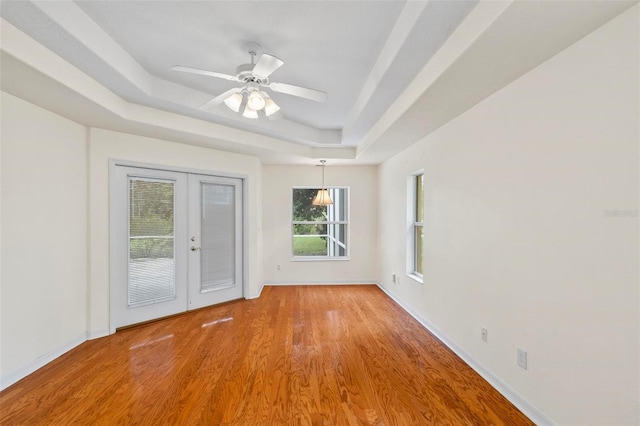 unfurnished room featuring french doors, hardwood / wood-style flooring, a raised ceiling, and ceiling fan