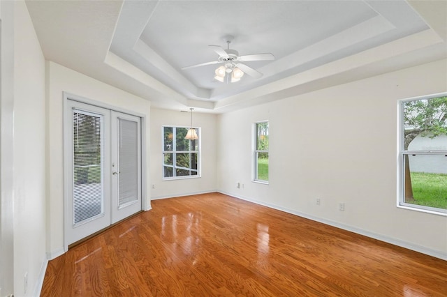 spare room with ceiling fan, hardwood / wood-style flooring, french doors, and a tray ceiling