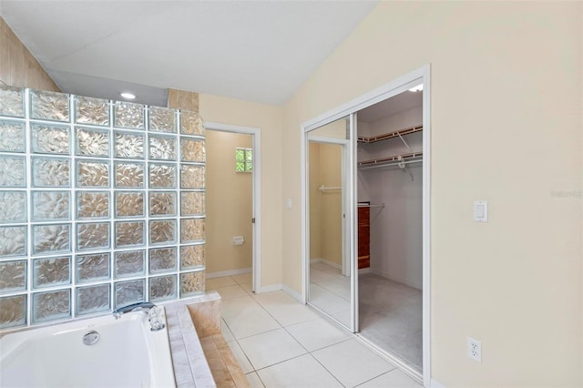 bathroom featuring tile patterned floors, lofted ceiling, and a tub to relax in