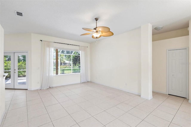 tiled empty room featuring ceiling fan and french doors