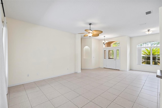 interior space with ceiling fan with notable chandelier and light tile patterned floors