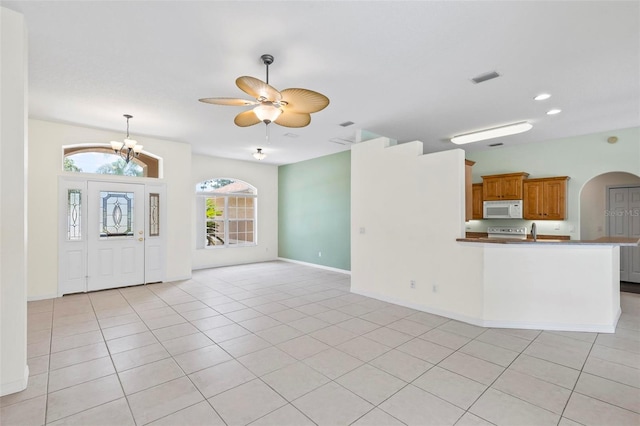 unfurnished living room with ceiling fan with notable chandelier, sink, and light tile patterned floors