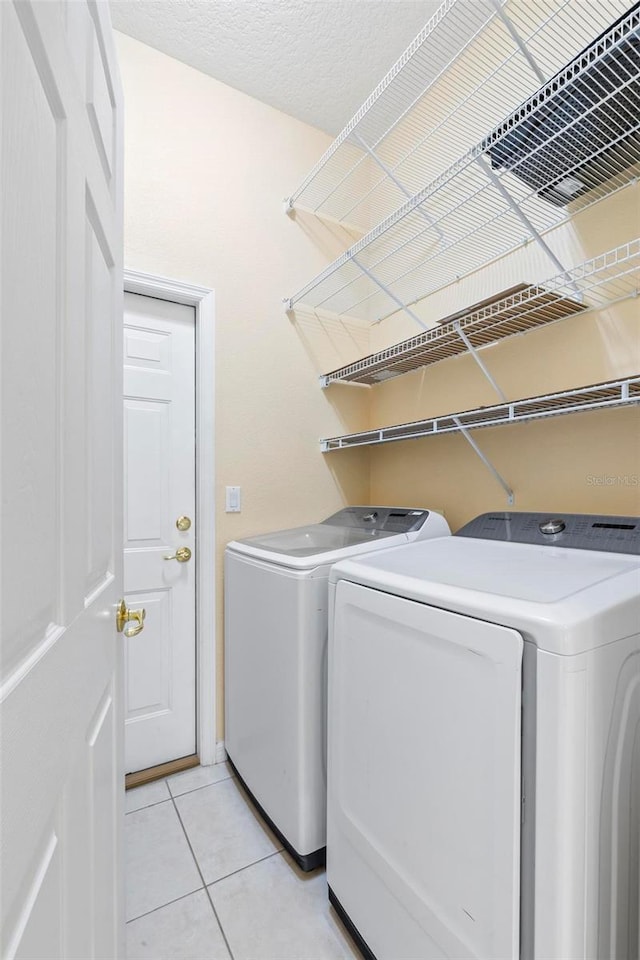 laundry room featuring washer and clothes dryer and light tile patterned floors