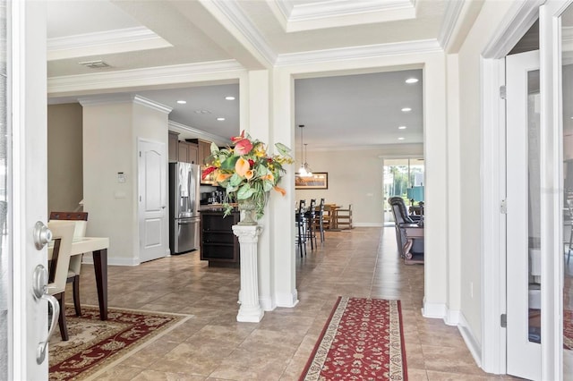 corridor featuring ornate columns, a raised ceiling, ornamental molding, and light tile patterned floors