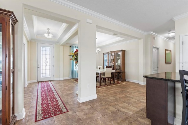 foyer featuring ornamental molding, tile patterned flooring, and a tray ceiling