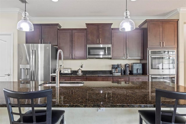 kitchen with dark stone countertops, a breakfast bar area, hanging light fixtures, and stainless steel appliances