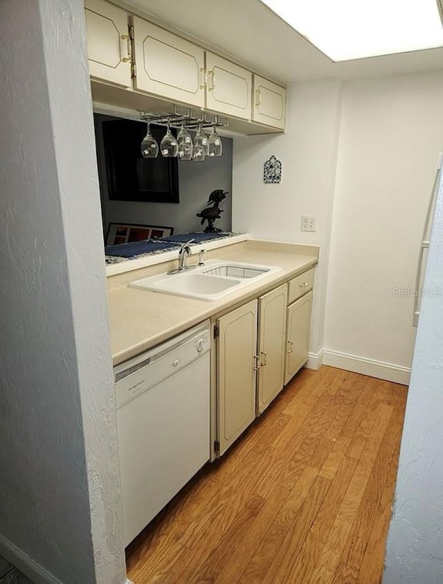 kitchen featuring white dishwasher, sink, and light hardwood / wood-style flooring