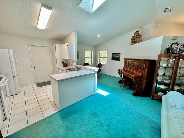 kitchen with white cabinetry, lofted ceiling with skylight, white appliances, sink, and light tile patterned floors