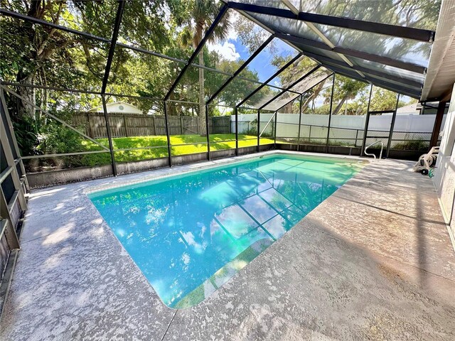 view of pool featuring glass enclosure and a patio area