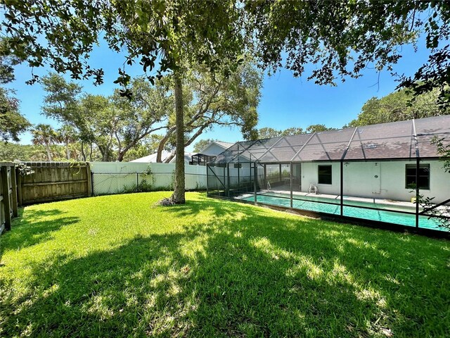 view of yard with a fenced in pool and glass enclosure