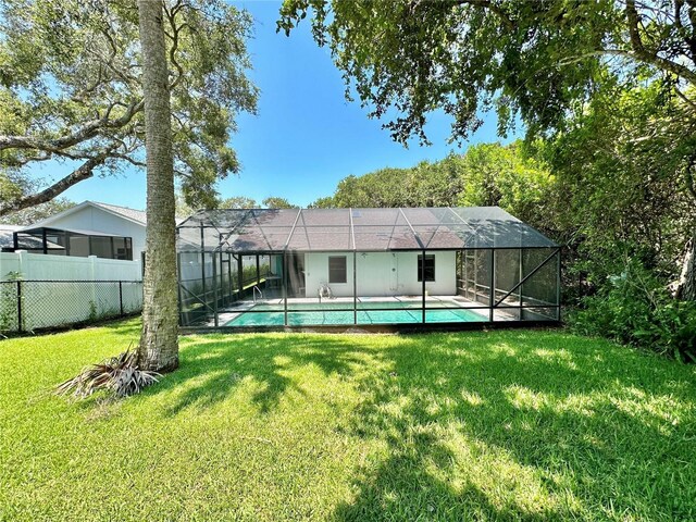 rear view of house featuring a yard, a lanai, and a fenced in pool