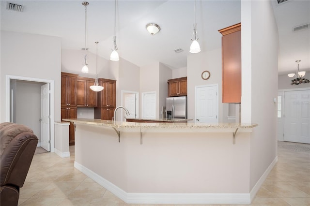 kitchen featuring decorative light fixtures, stainless steel fridge, a breakfast bar, and kitchen peninsula