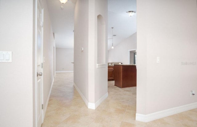 hallway with vaulted ceiling and light tile patterned floors