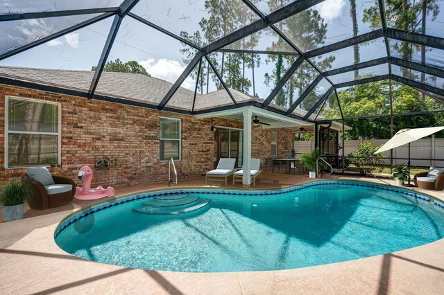 view of swimming pool with ceiling fan, a lanai, and a patio