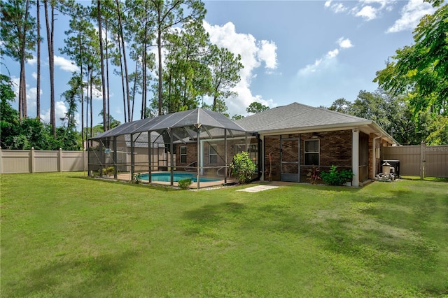 rear view of property with glass enclosure, a fenced in pool, and a lawn