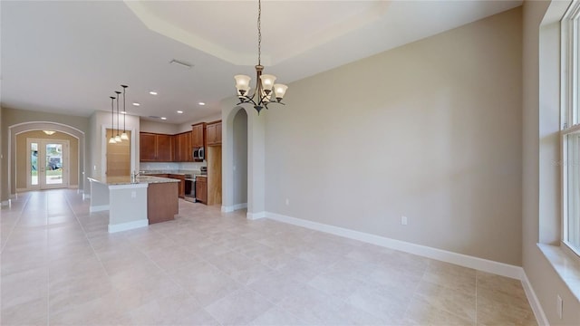 kitchen featuring arched walkways, stainless steel appliances, open floor plan, and decorative light fixtures