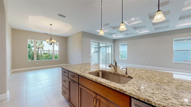 kitchen with visible vents, a sink, decorative light fixtures, and light stone countertops