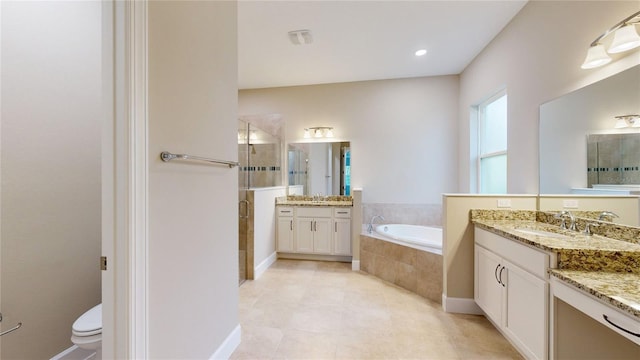 bathroom featuring a garden tub, toilet, two vanities, a sink, and a shower stall