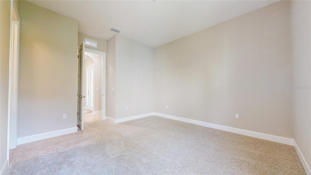 empty room featuring light carpet, visible vents, and baseboards