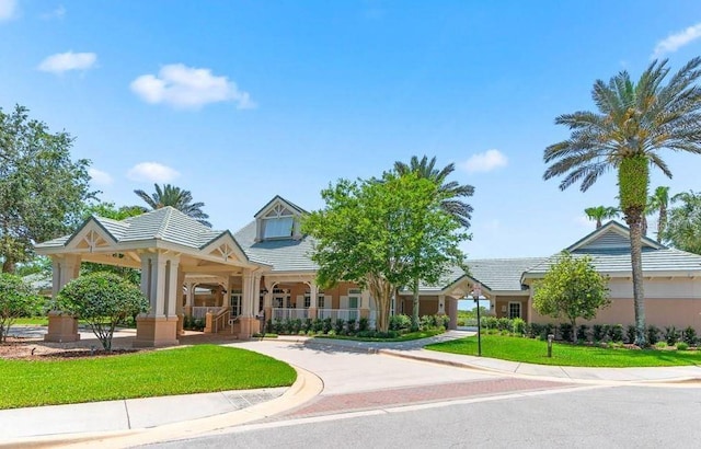 view of front of property featuring stucco siding, a tiled roof, a porch, and a front yard