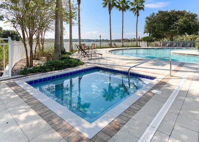 pool with fence, a community hot tub, and a patio