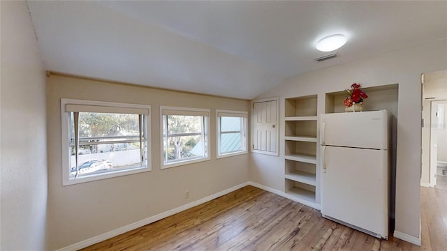 interior space featuring baseboards, light wood-style flooring, visible vents, and a healthy amount of sunlight