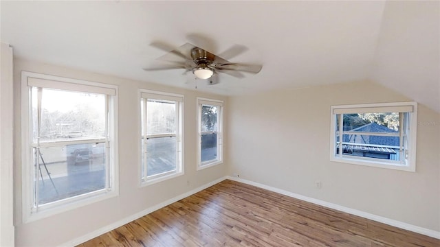 unfurnished room with lofted ceiling, light wood-style floors, baseboards, and a ceiling fan