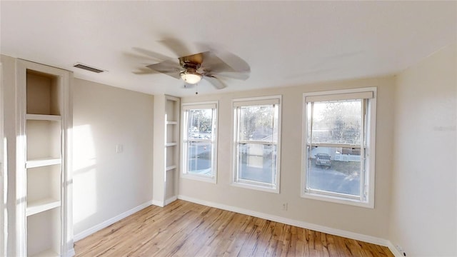 empty room featuring light wood-type flooring, baseboards, visible vents, and ceiling fan