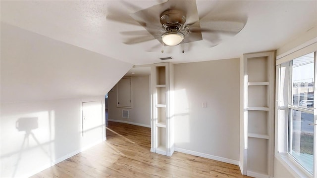 additional living space featuring light wood-style floors, ceiling fan, visible vents, and vaulted ceiling