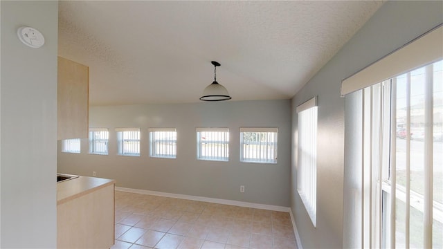 unfurnished dining area featuring a textured ceiling, baseboards, and light tile patterned floors