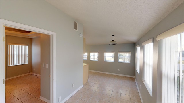 spare room with light tile patterned floors, visible vents, vaulted ceiling, and a textured ceiling